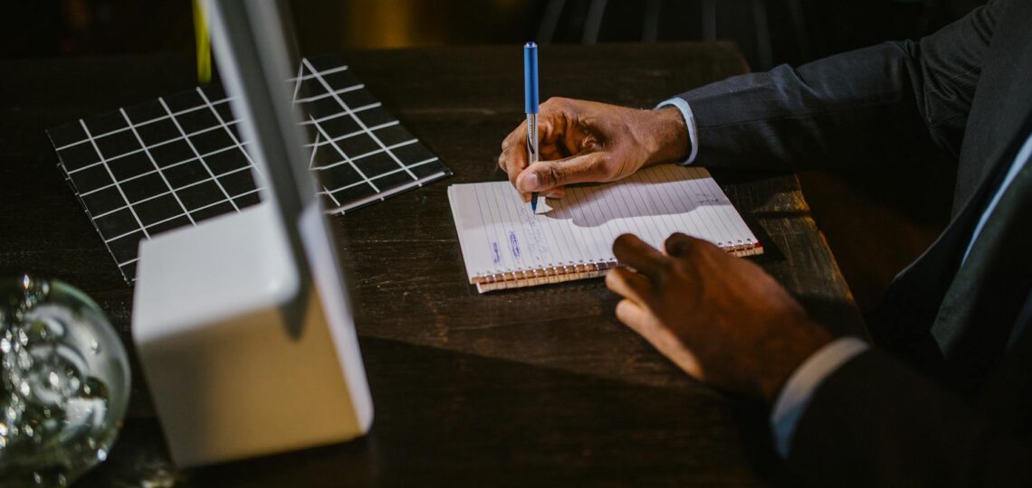 homem no escritorio fazendo anotações em um bloco de notas