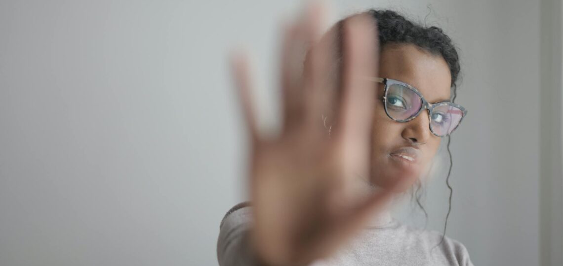 mulher esticando a mão para frente sinalizando basta à procrastinação