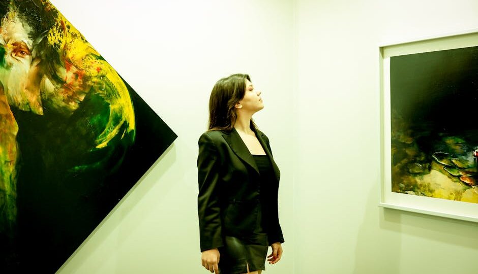 A woman in a black outfit admiring abstract paintings in a modern art gallery.