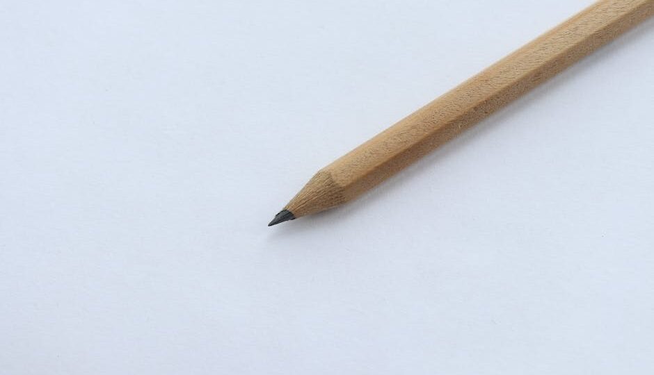 Minimalist close-up of a wooden pencil on white paper, highlighting simplicity and creativity.