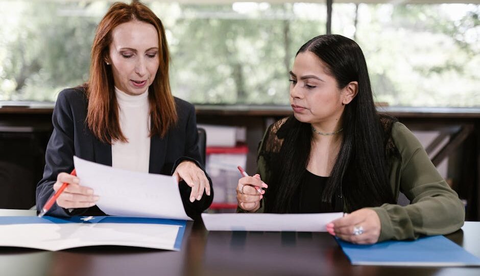 Two professional women reviewing documents in a well-lit office setting.