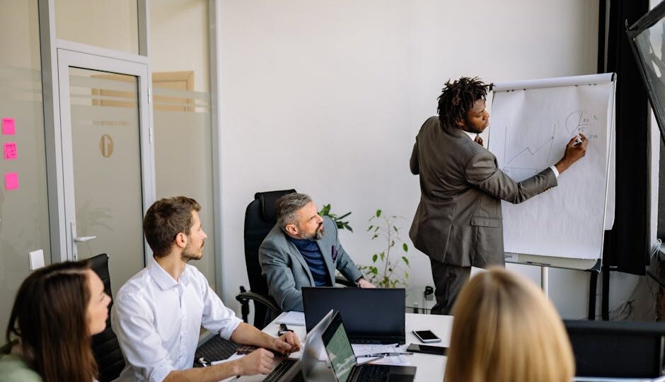 A diverse team in a modern office engaged in a strategic business meeting led by a presenter.