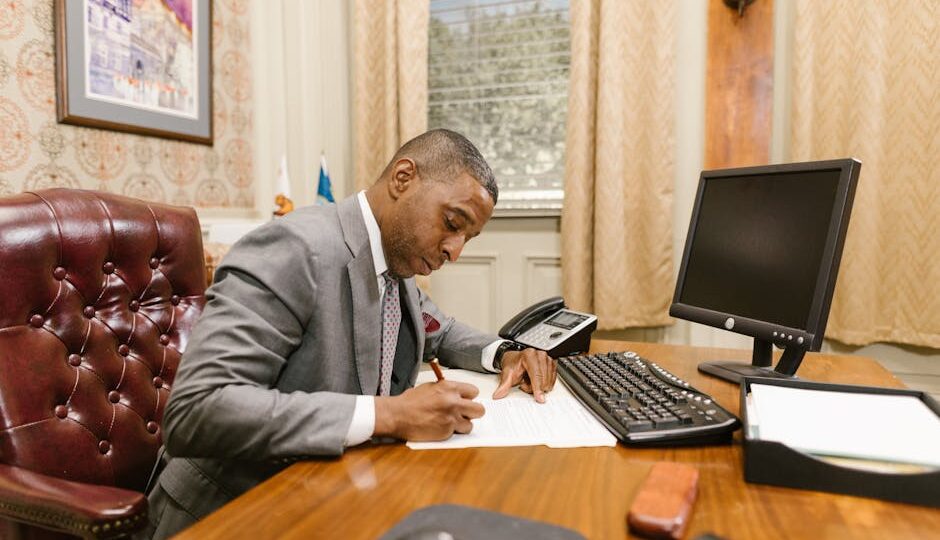 Lawyer writing at desk in a law office, focusing on documents.