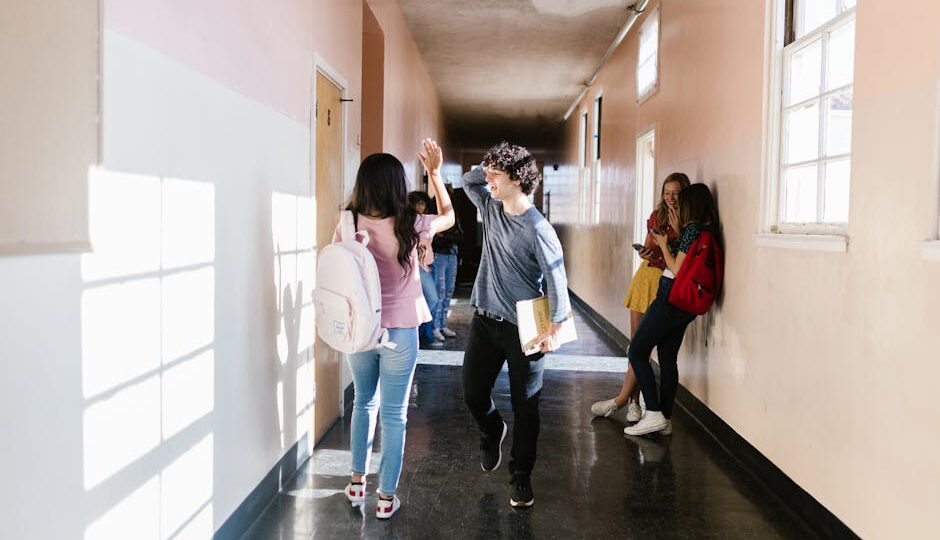 Teenagers interacting and socializing in a high school hallway during the day.
