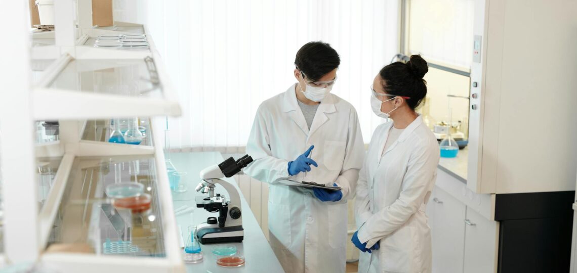 homem e mulher cientistas analisando dados em um laboratório usando EPI