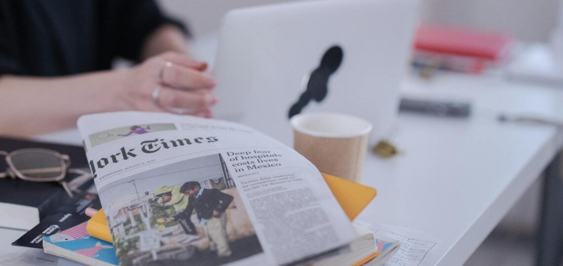 jornalista analisando diversos dados em jornais impressos e online