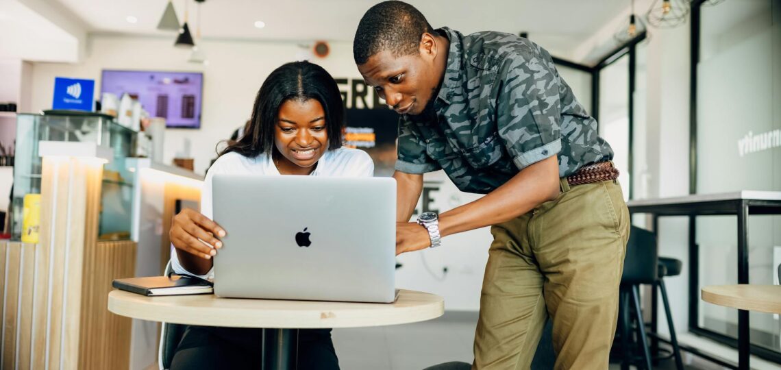 homem e mulher no escritorio moderno conversando olhando para a tela do laptop
