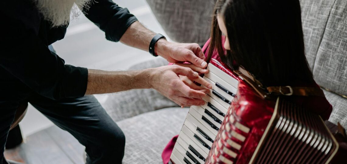 professor ensina uma menina de cerca de 8 anos a tocar sanfona