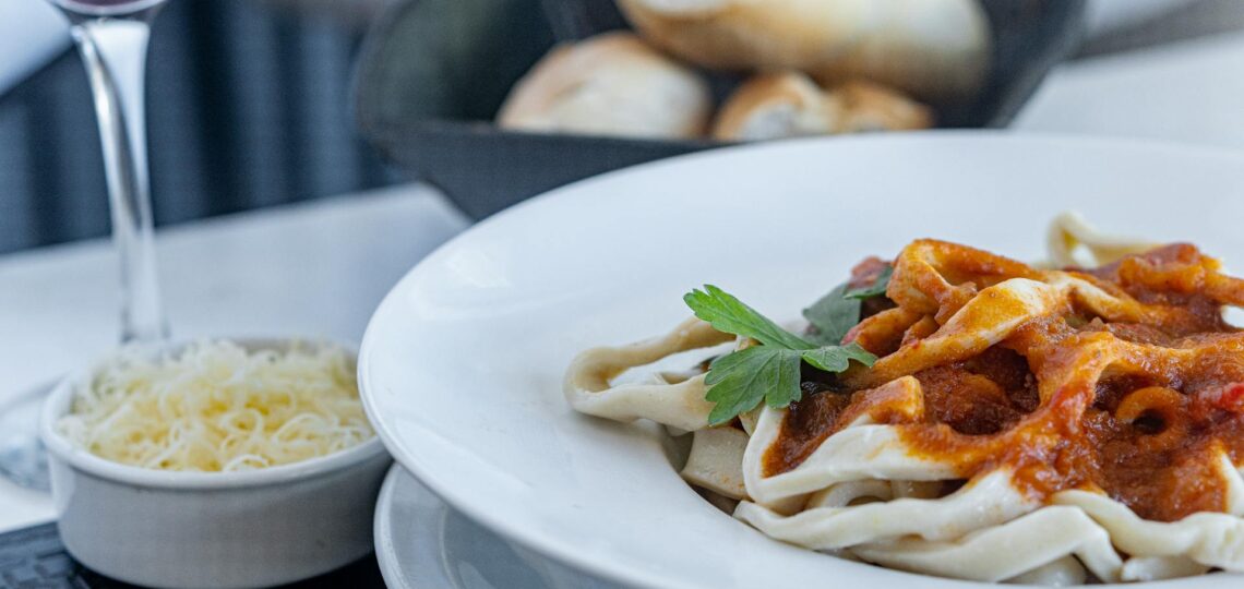 prato com massa recém servido na cozinha e um pote com queijo ralado